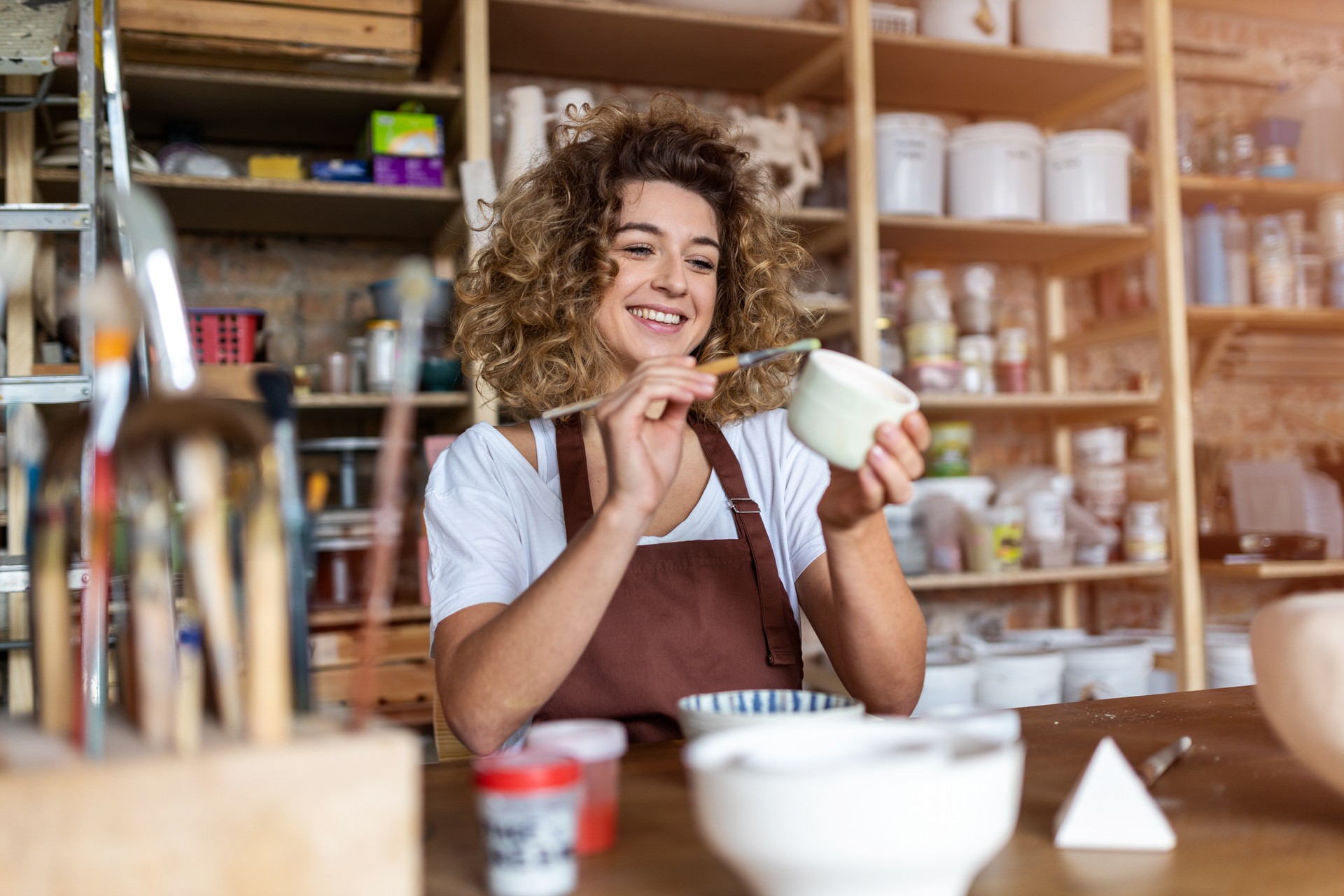 Craftsperson painting a bowl made of clay in art studio